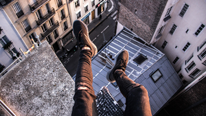 person sitting on tall building with legs over the side