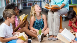 teacher reading to a group of children in a library