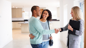 female estate agent shaking hand with couple looking around a house