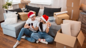 couple sat on the floor among boxes while wearing Christmas hats